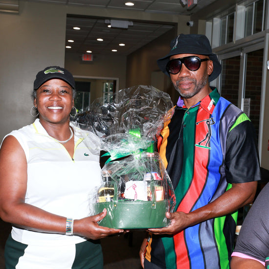 Man wearing the River Flows Polo rainbow stripe with a gift basket at the clubhouse