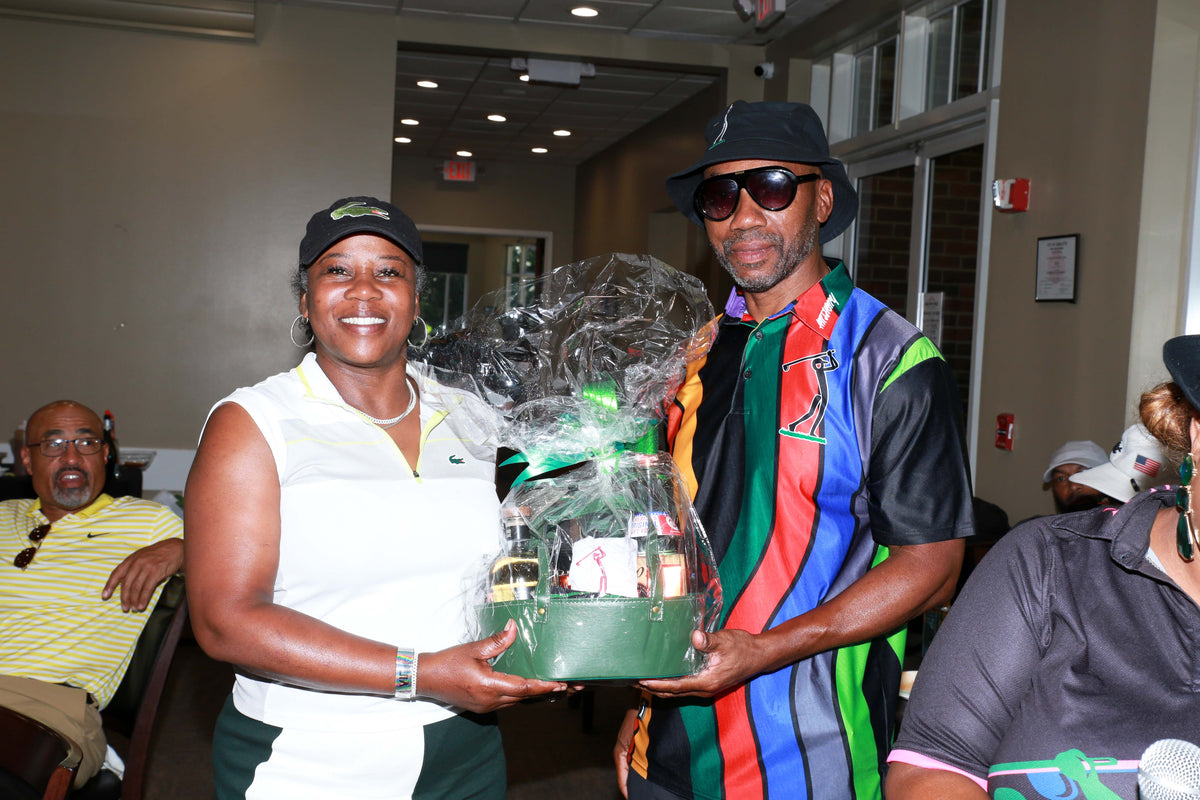 Man wearing the River Flows Polo rainbow stripe with a gift basket at the clubhouse